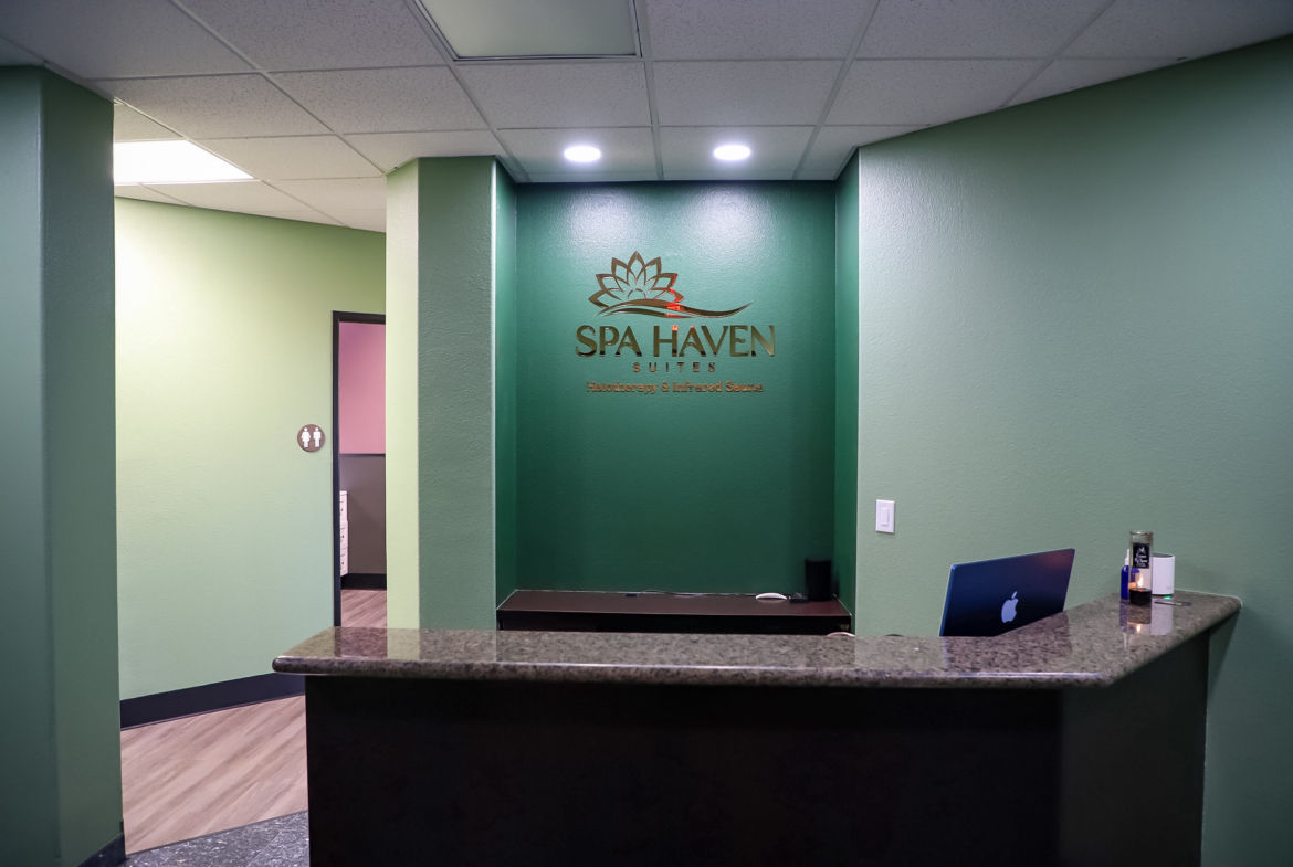 Beautiful salon reception with green walls, modern decor, and a sleek granite counter. Ideal for hair, spa, and beauty professionals seeking salon space rental.