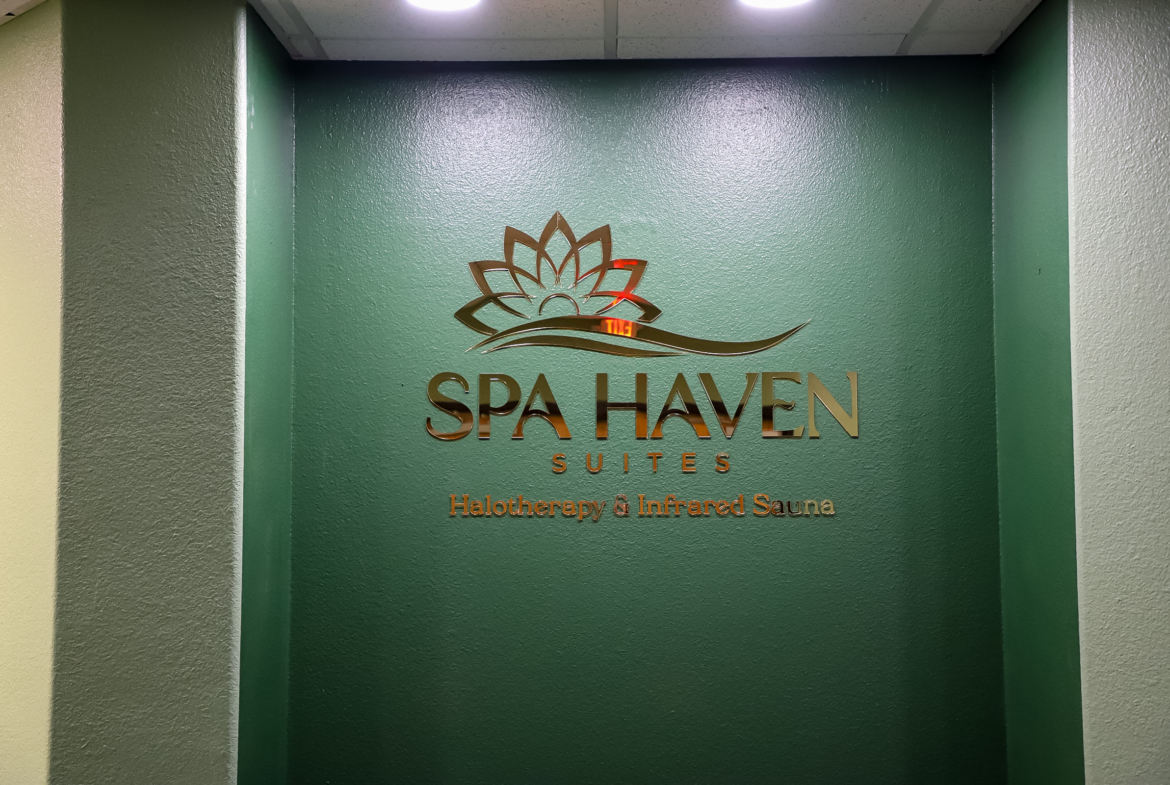 Modern spa signage on green wall at Spa Haven.