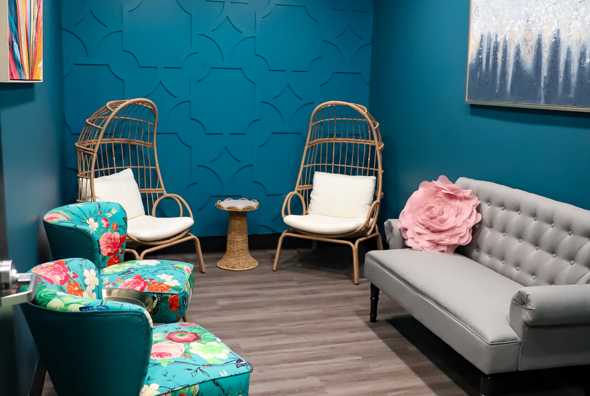 Cozy salon lounge with colorful chairs and calming blue walls.