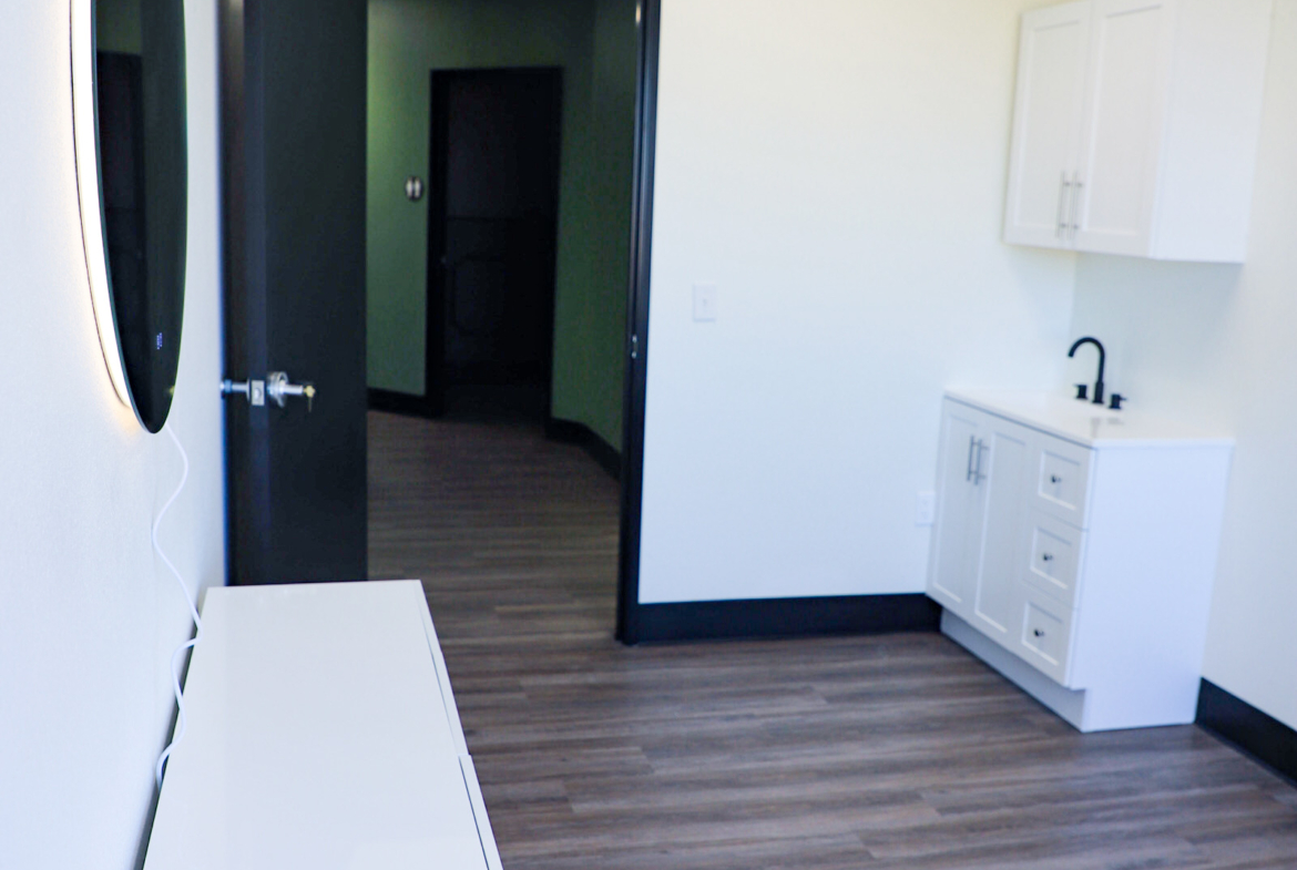 Bright, clean salon room with small sink and white cabinetry for hair and beauty services.