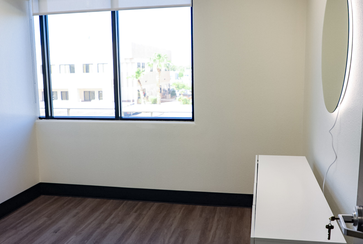 Bright, empty salon room with large window, contemporary decor, ideal for salon renters.