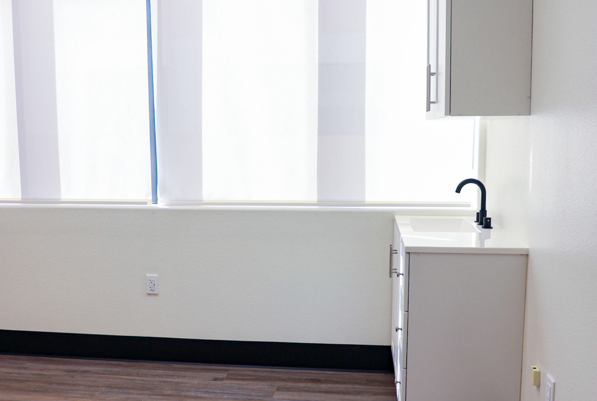 Bright salon area featuring a small kitchenette with sink and cabinets for clients' convenience.