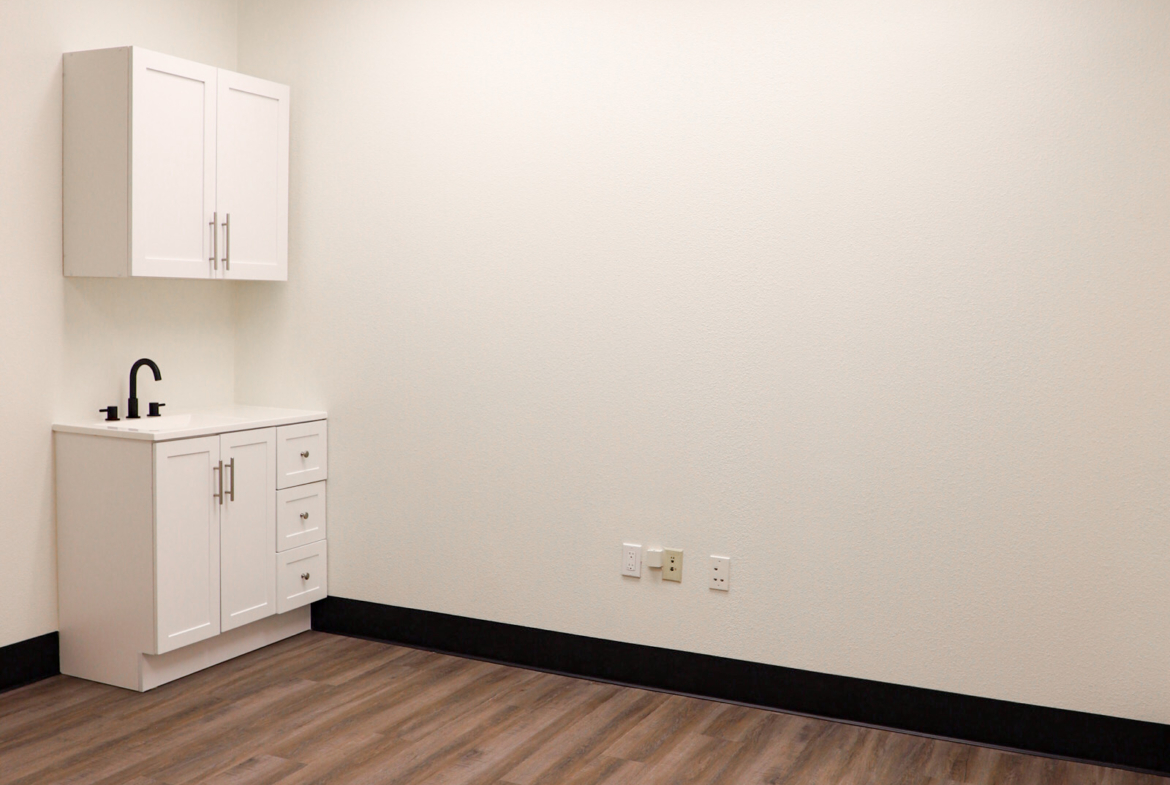 Bright, clean salon rental room with wood flooring, white walls, and ceiling lighting.