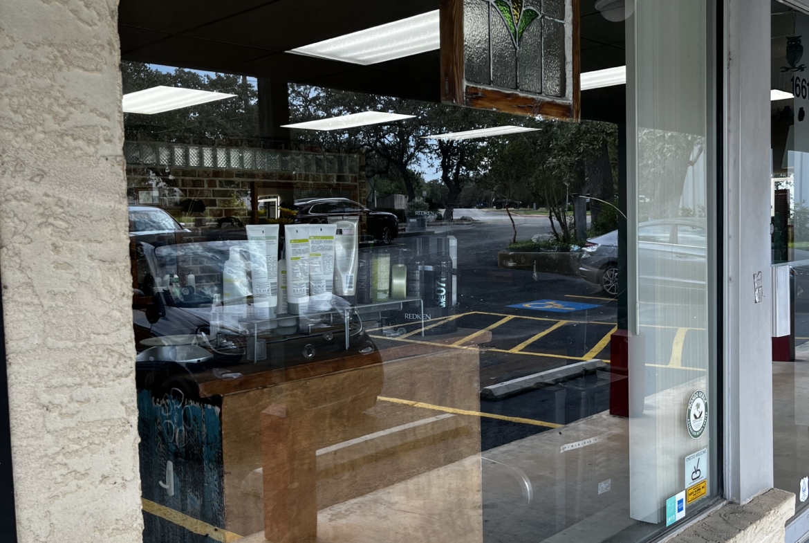 High-quality image of salon space rental storefront with large glass window, showing interior lighting and parking availability.