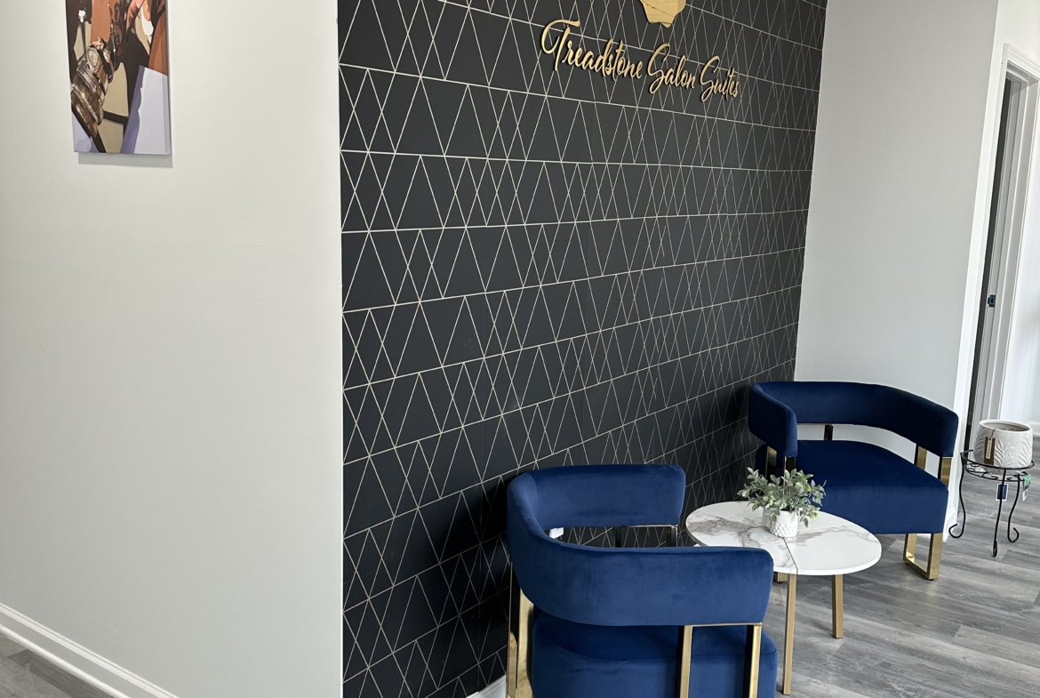 Bright, stylish salon decor featuring elegant seating and a geometric accent wall for relaxing client comfort.