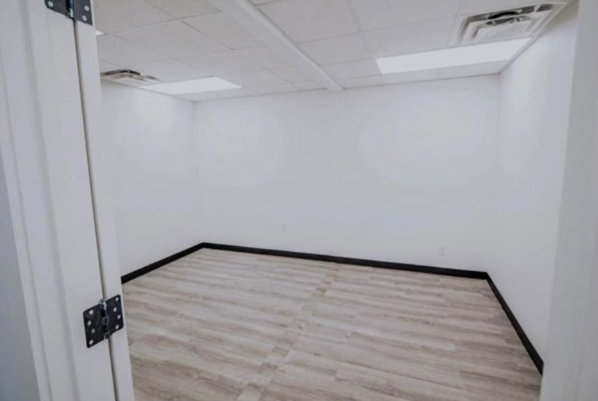 Empty salon room with white walls and wood flooring for rent.