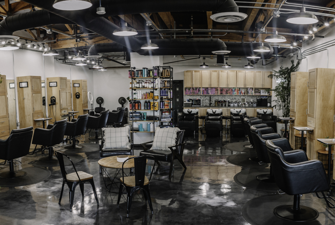Stylish hair salon interior with multiple styling chairs, wash stations, and hair product shelves.
