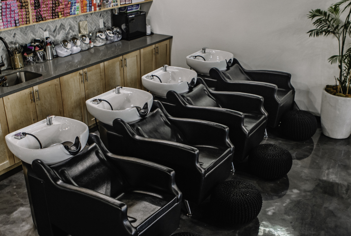 Modern hair salon with black wash basins and comfortable chairs for client hair washing services.