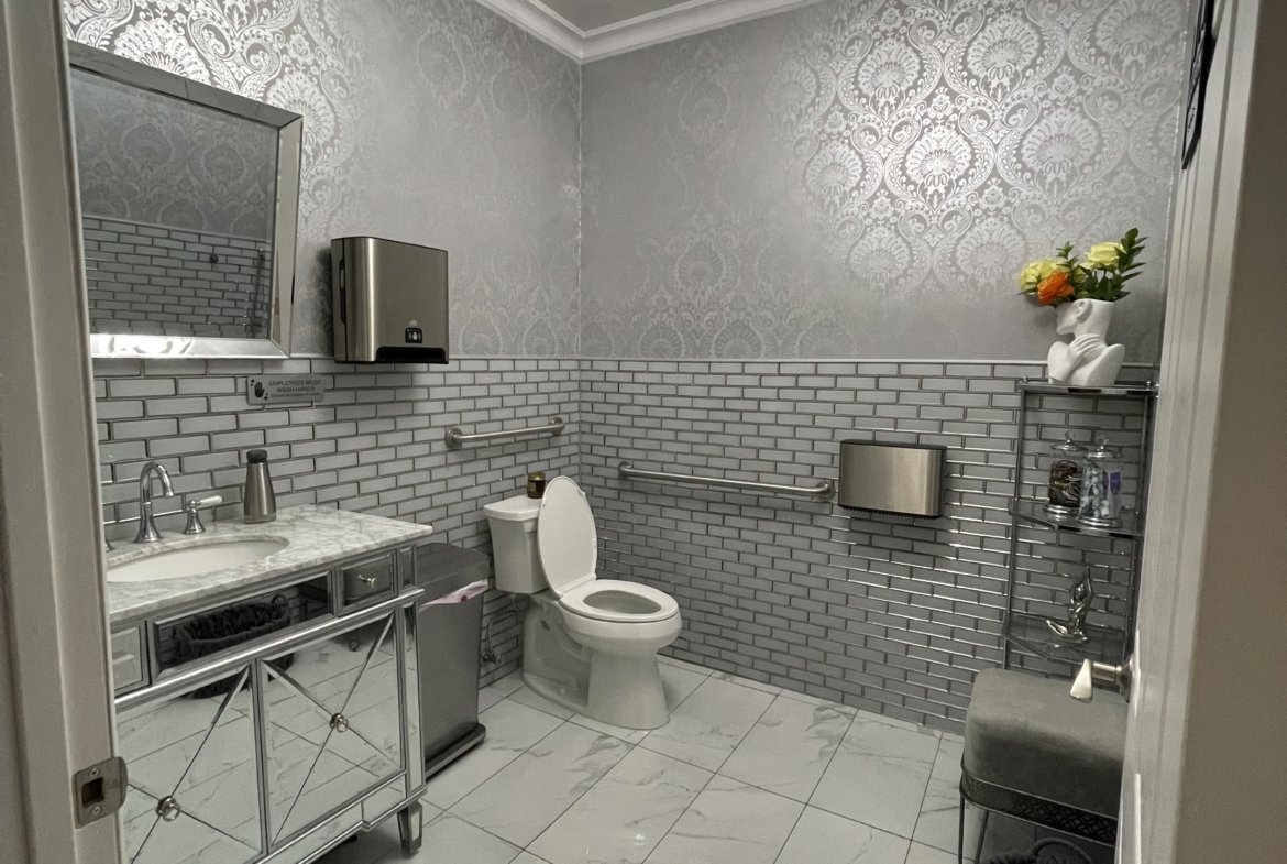 Stylish salon bathroom featuring marble countertop, silver accents, and contemporary lighting.