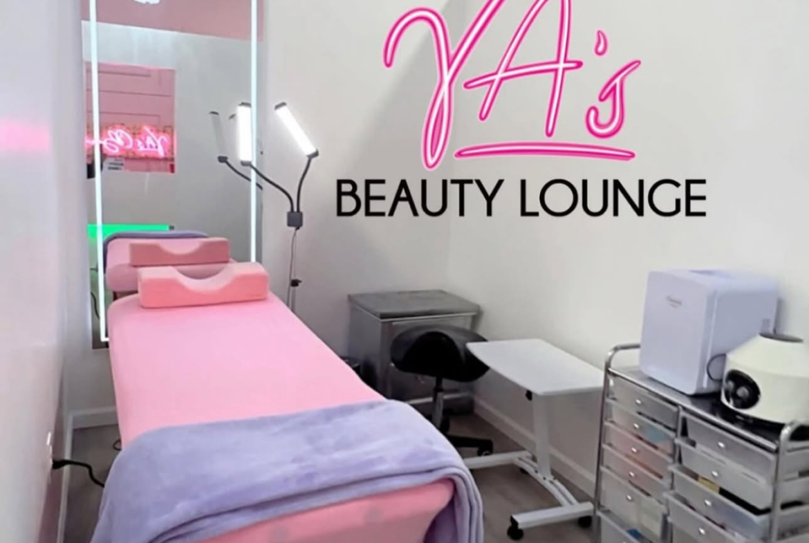 Comfortable beauty lounge with pink spa bed and professional equipment setup.