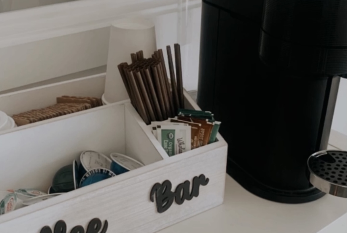 A small coffee station with a coffee maker and supplies in a hair salon, perfect for salon renters to enjoy quality coffee while working.