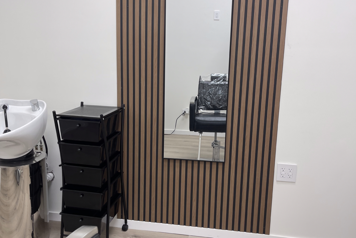 Clean, minimal salon space with mirror, seating, and storage for hairdresser use.