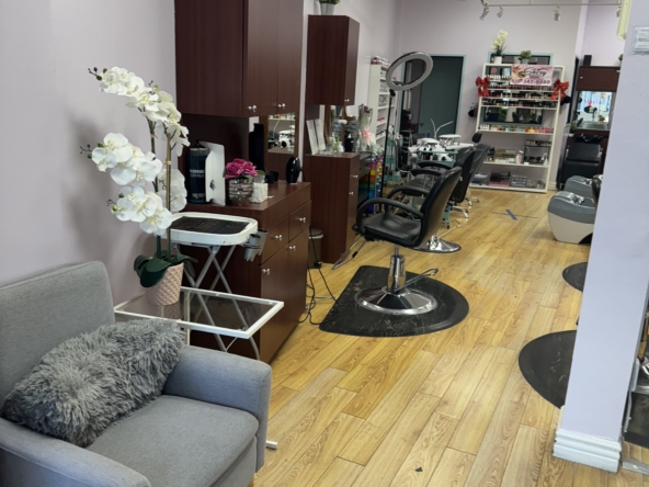 Bright salon with styling chairs, mirrors, nail polish display, and cozy seating space.
