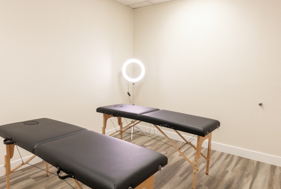 Quiet massage therapy room with two treatment tables and professional lighting.