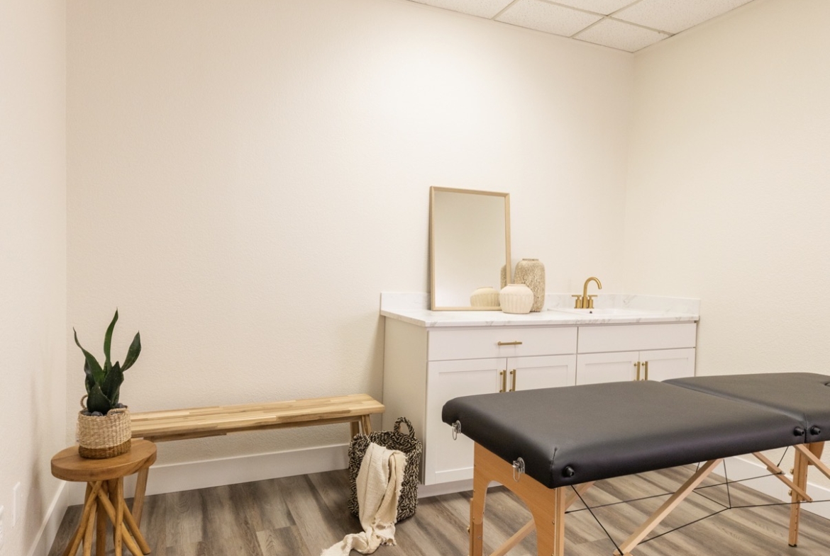 Bright, clean salon room featuring massage table, modern decor, and relaxing atmosphere.