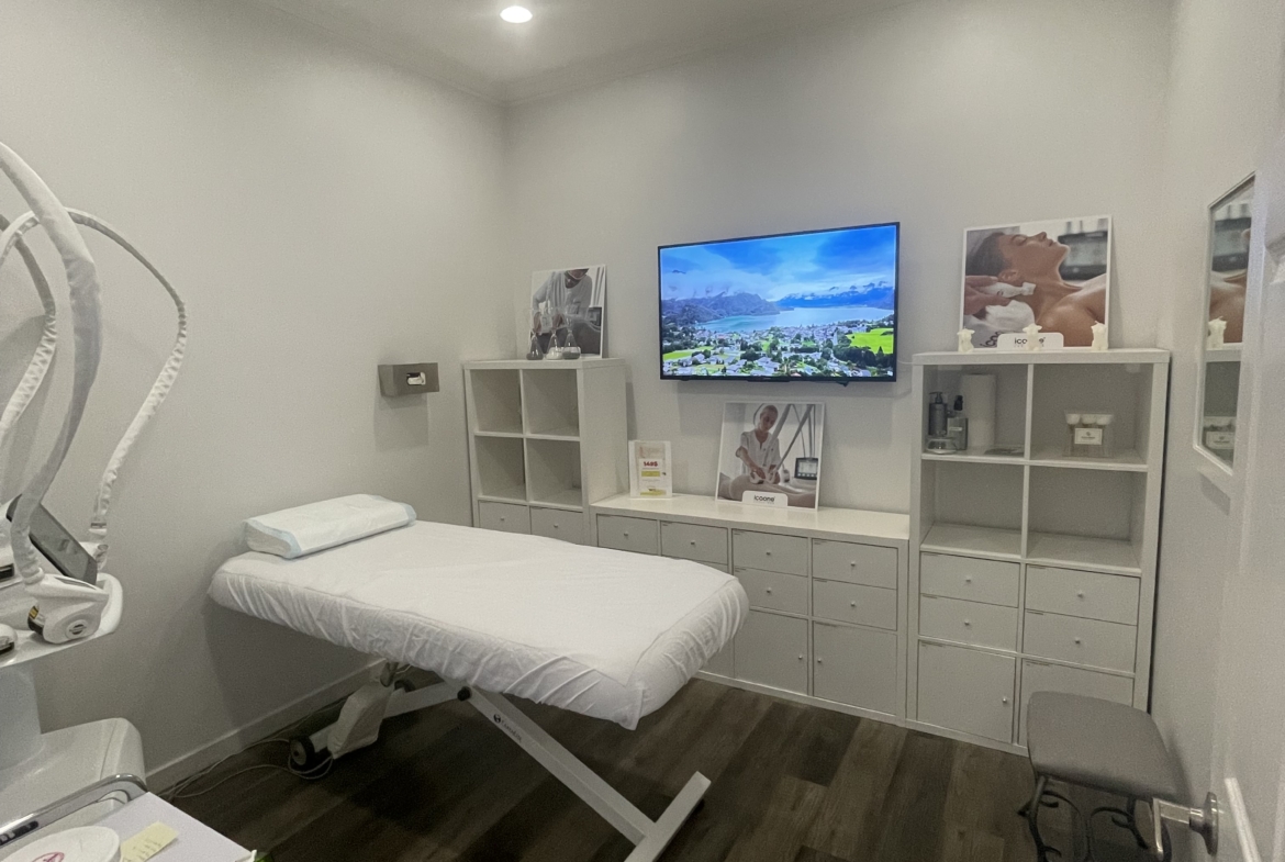 Comfortable salon treatment room with massage table, TV, and professional decor.