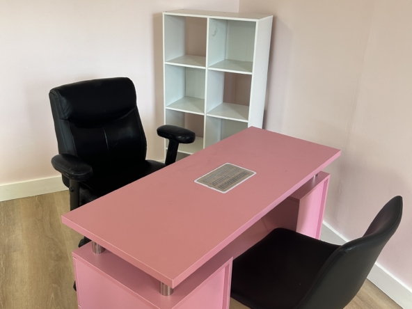 Bright pink modern salon desk with vent, paired with black office chair in stylish salon setting.