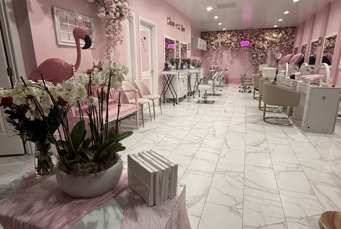 Bright pink salon with floral accents, modern chairs, and elegant decor for a chic beauty experience.