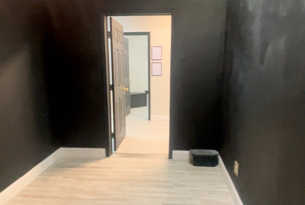 Chic salon room featuring black walls, modern decor, and light wooden floors for a trendy vibe.