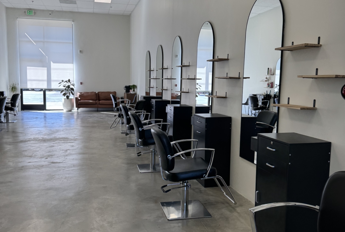 Henry text for alt: Modern hair salon with styling chairs, mirrors, and shelves for beauty services.