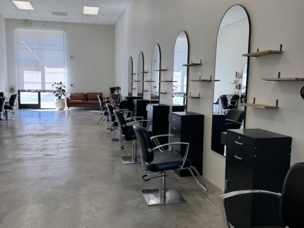 Henry text for alt: Modern hair salon with styling chairs, mirrors, and shelves for beauty services.