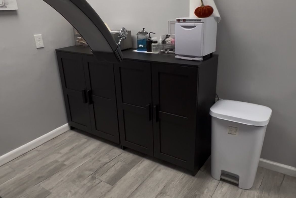 Clean salon station with black cabinet, sink, and countertop for beauty services.