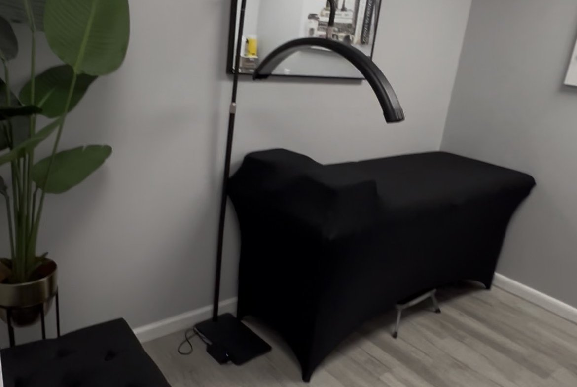 Clean salon room with massage table, mirror, and seating area for beauty or wellness professionals.