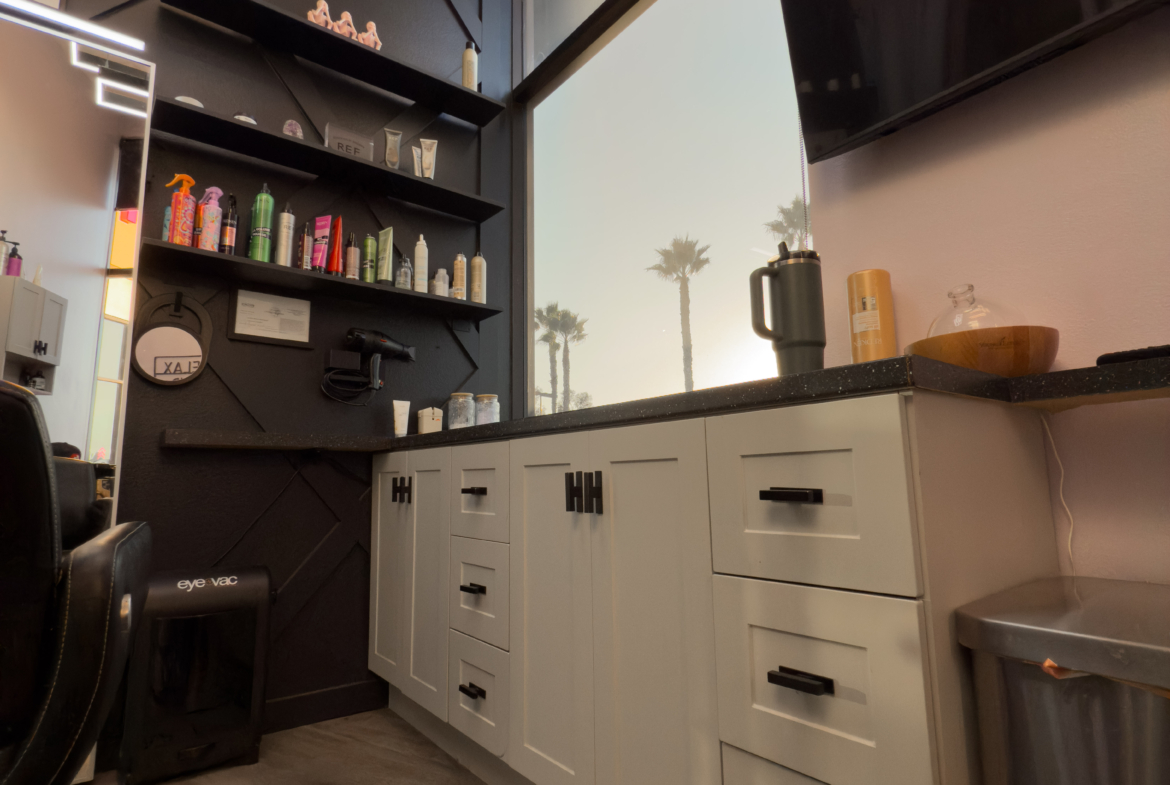 High-quality salon workspace featuring storage cabinets, beauty products, and large windows with scenic palm views.