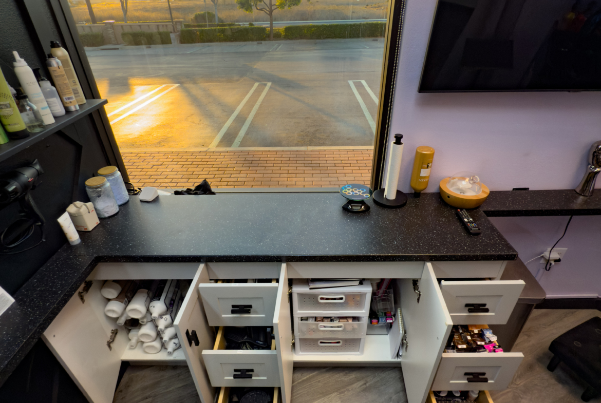 Bright salon workspace with cabinets and tools for hairstyling and beauty services.