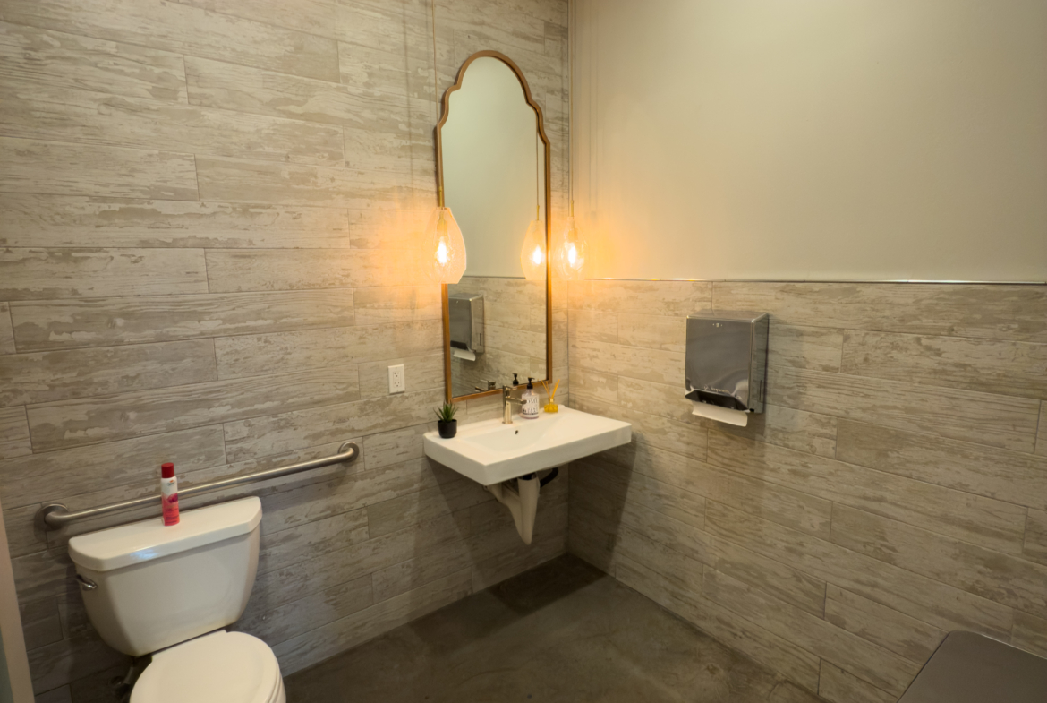 Bright salon bathroom featuring contemporary design, elegant lighting fixtures, and essential facilities.