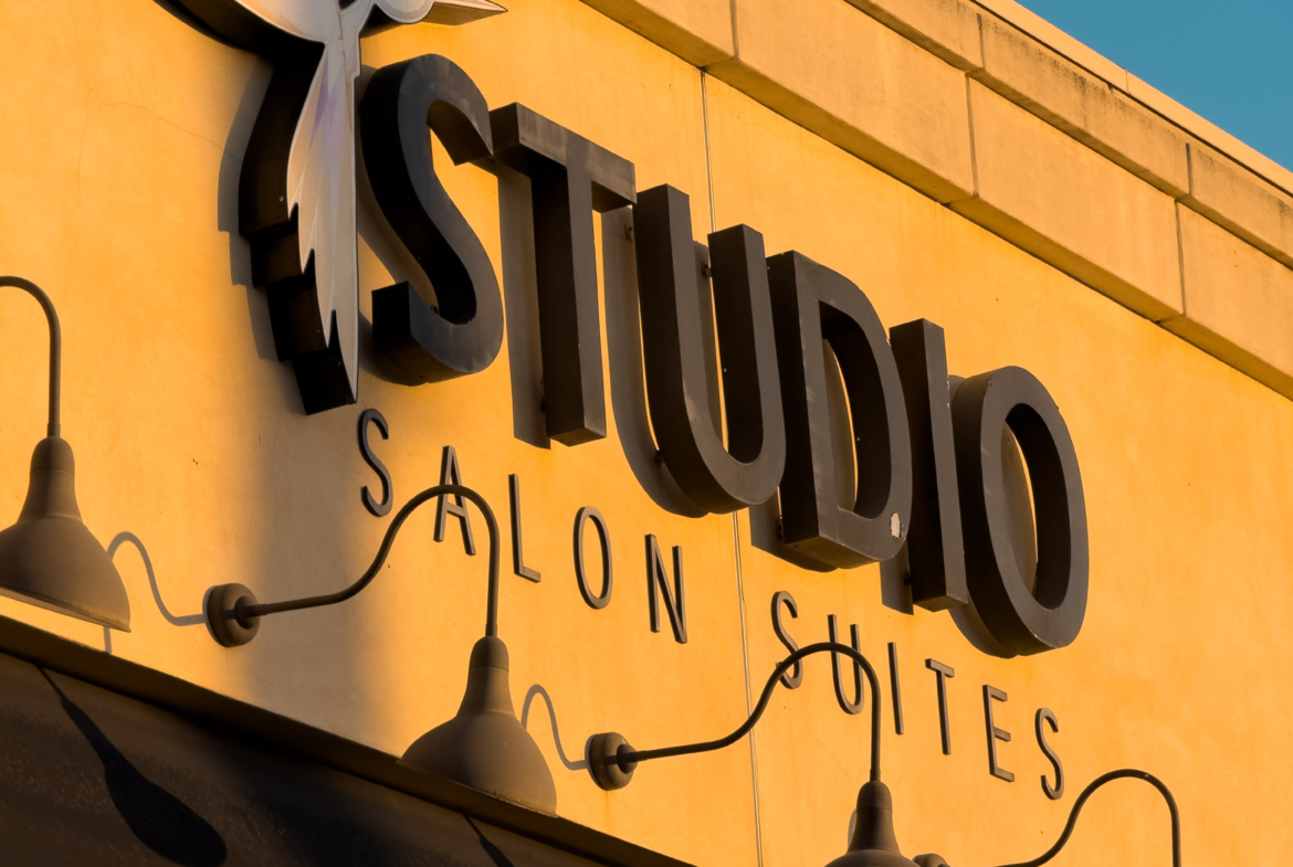 Bright yellow building with "Studio Salon" sign and decorative hummingbird logo.