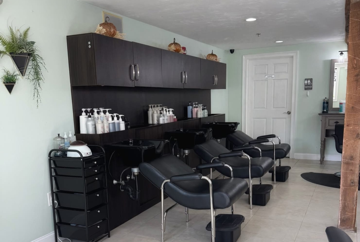 Modern hair salon wash bowls with black chairs and salon supplies.