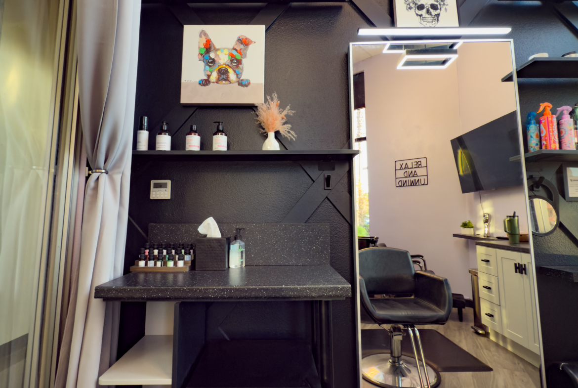 Stylish salon interior with black decor, artwork, and styling area for rent.
