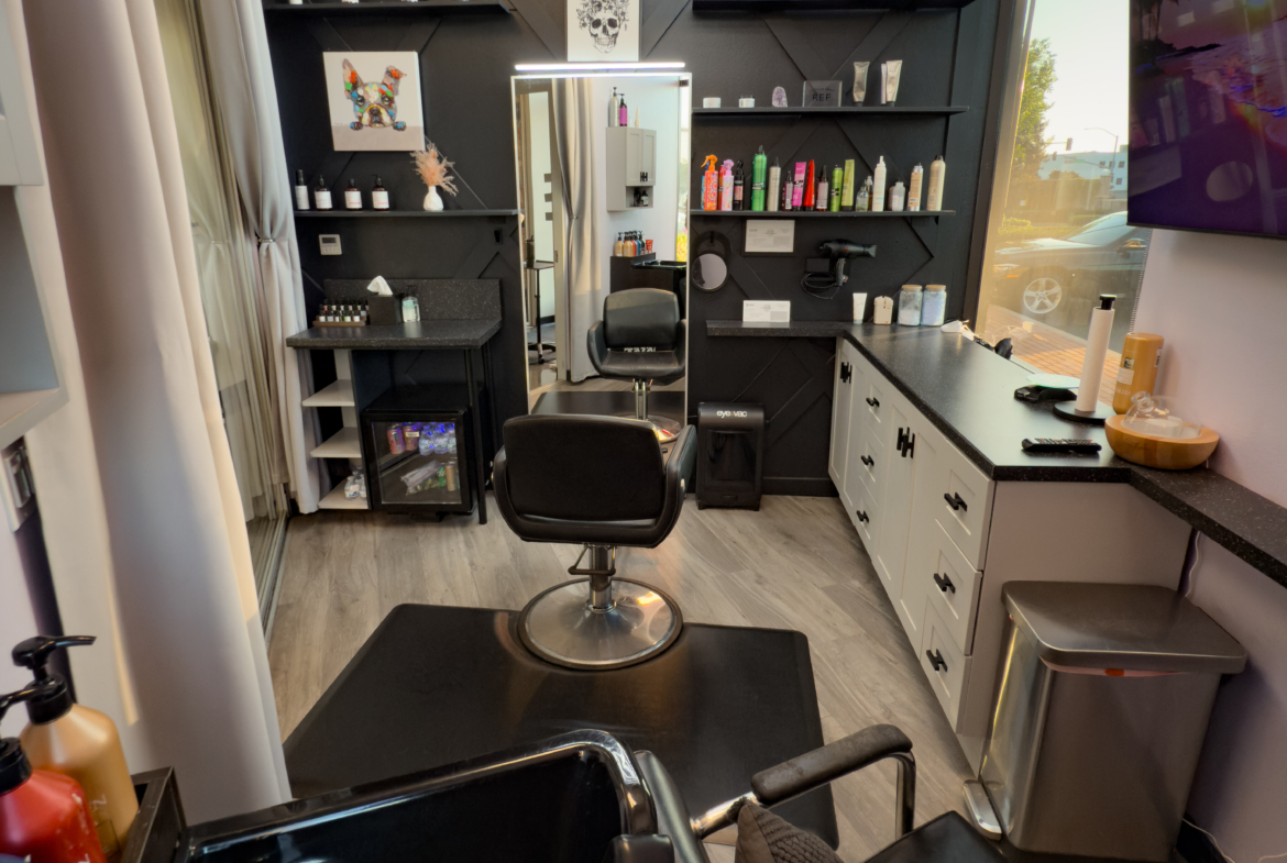 Bright interior of a professional salon with black and white decor, styled shelves, and contemporary lighting.