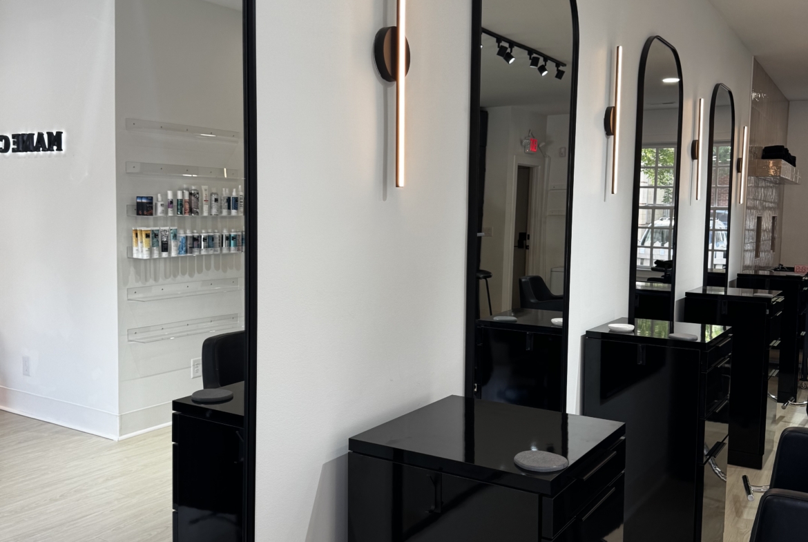 Stylish salon station featuring black cabinetry, frameless mirrors, and contemporary lighting.