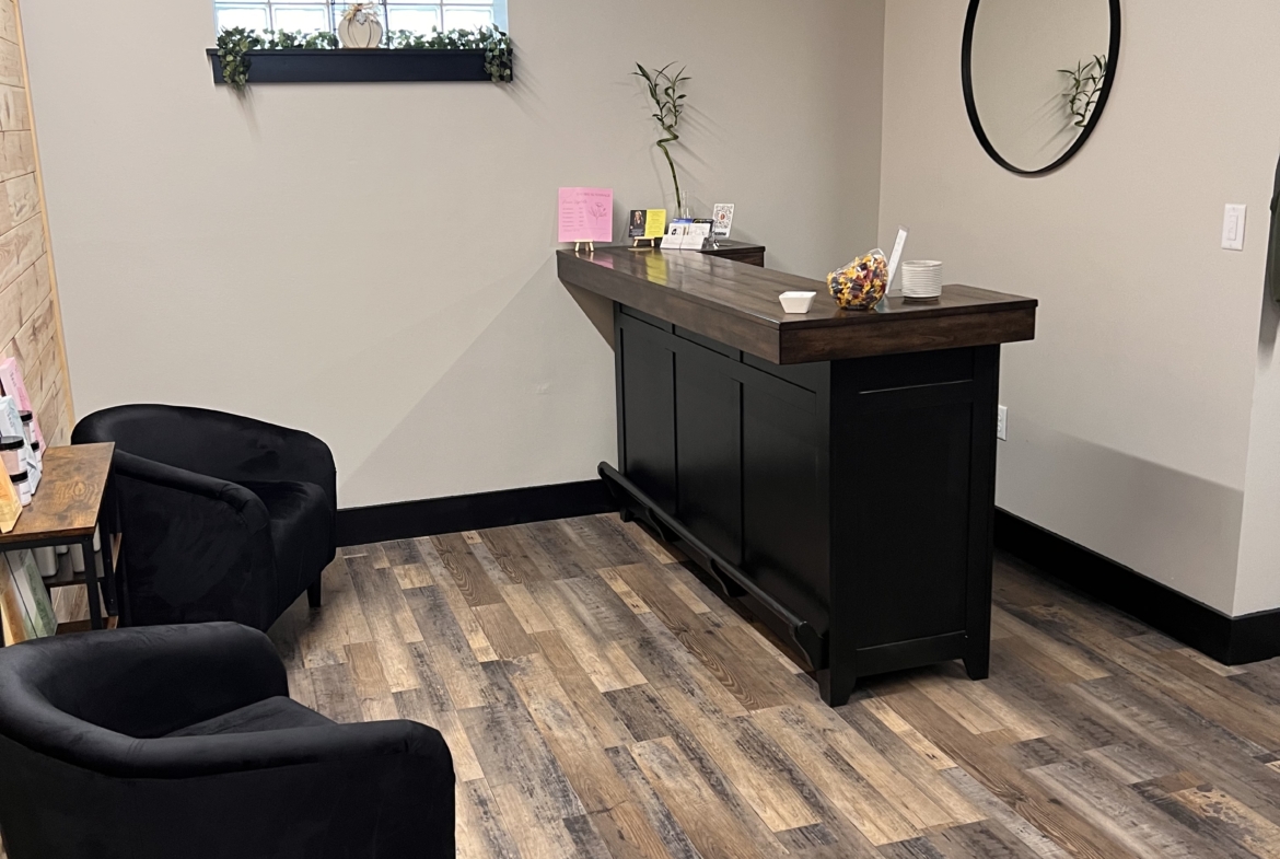 Stylish salon reception with black chairs, wooden flooring, and minimalist decor.