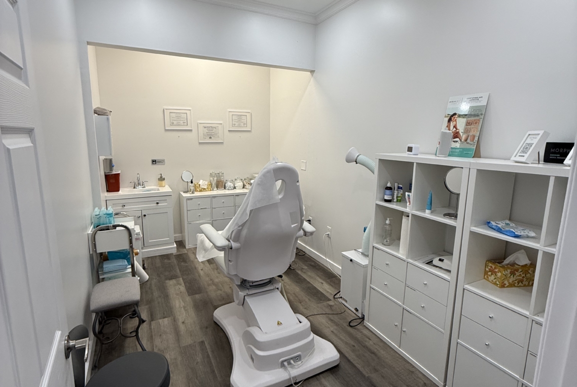 Comfortable beauty salon with white treatment chair and organized storage shelves for skincare products.
