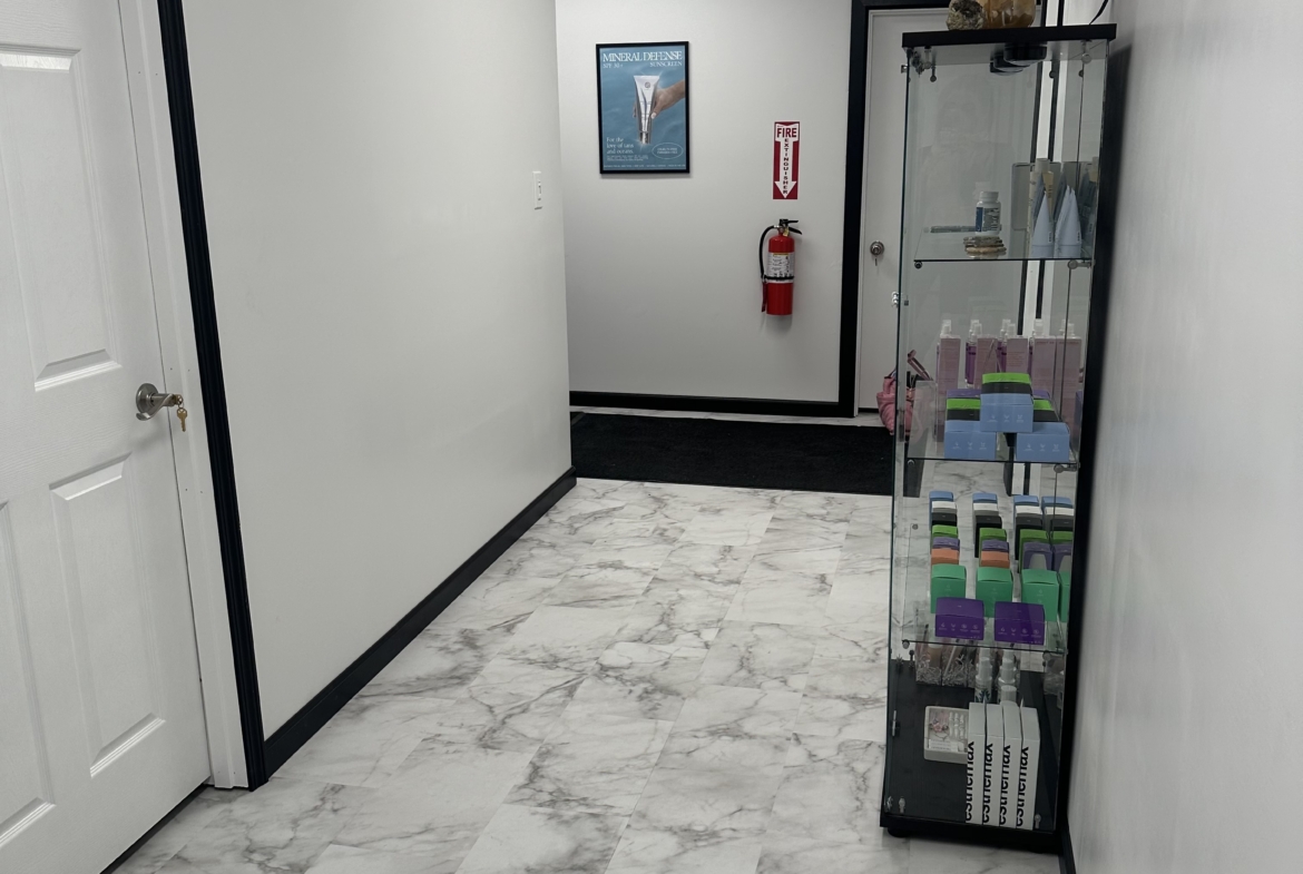 Stylish salon interior featuring marble tiles, display shelf with hair products, clean white walls.