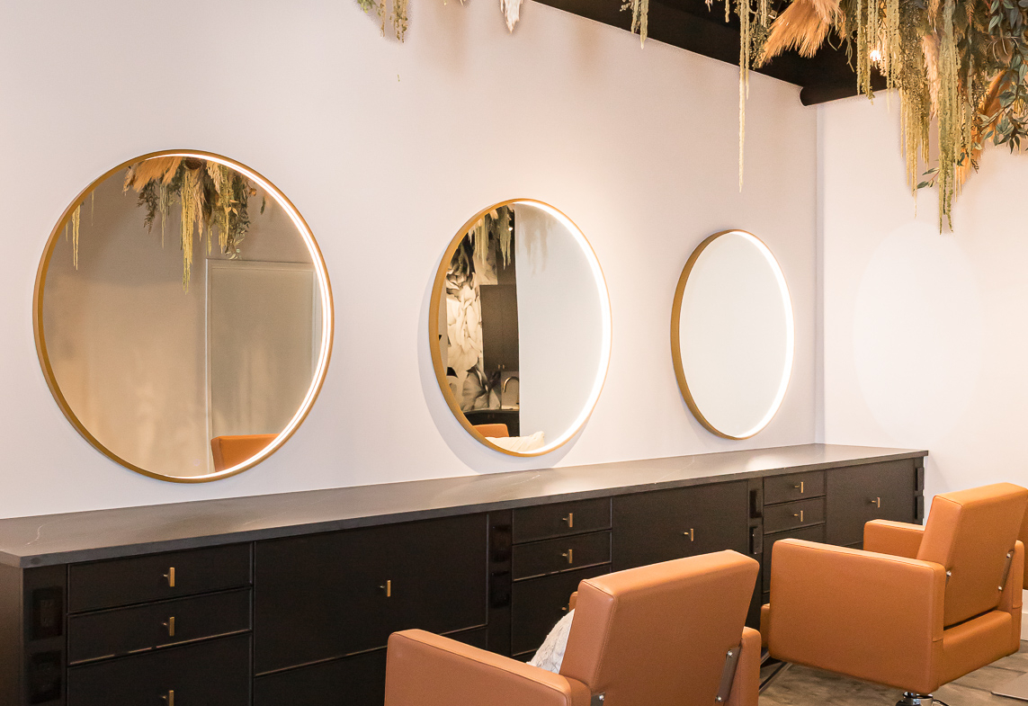 Stylish salon station with mirrors, brown chairs, and elegant decor.