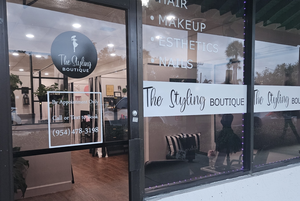 A stylish salon storefront advertising hair, makeup, esthetics, and nails services with appointment info.