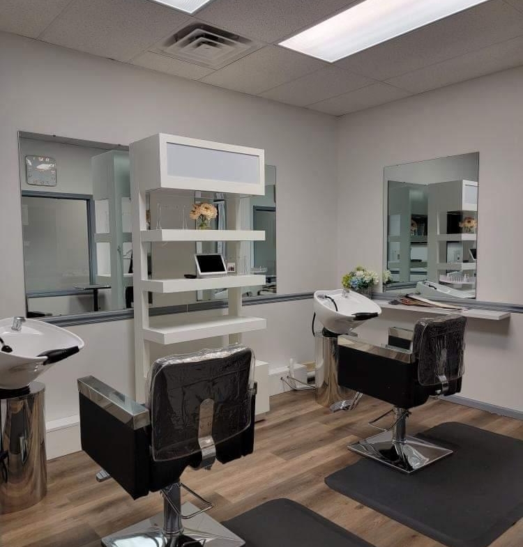 A contemporary salon station with black chairs, mirrors, and washing sinks for hair treatments.