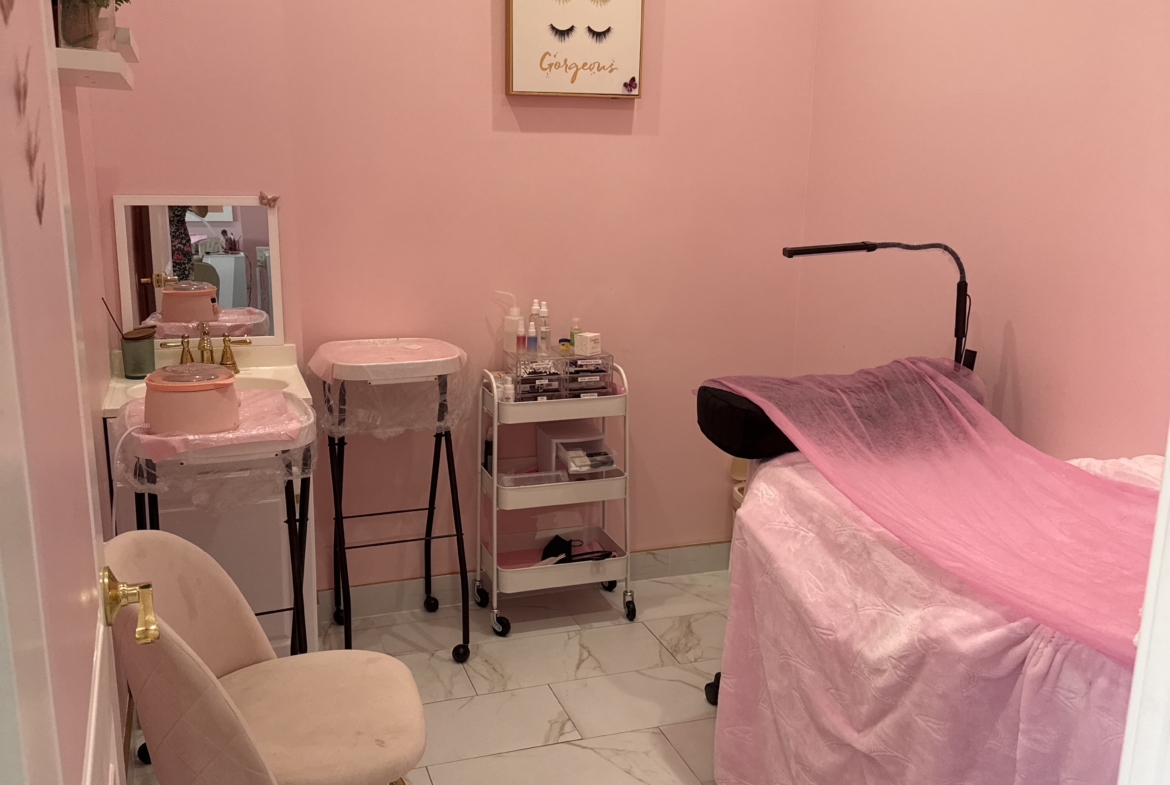 Beautiful pink-themed salon room with beauty treatment bed and stylish decor.