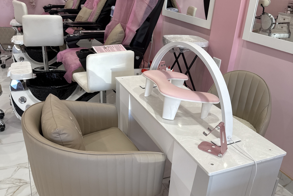 Pink-themed salon with reclining chairs and manicure table in a chic, floral decor environment.