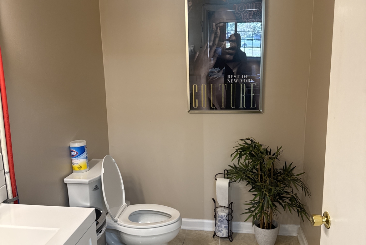 Bright, clean bathroom in a professional salon rental with a decorative plant and framed artwork.