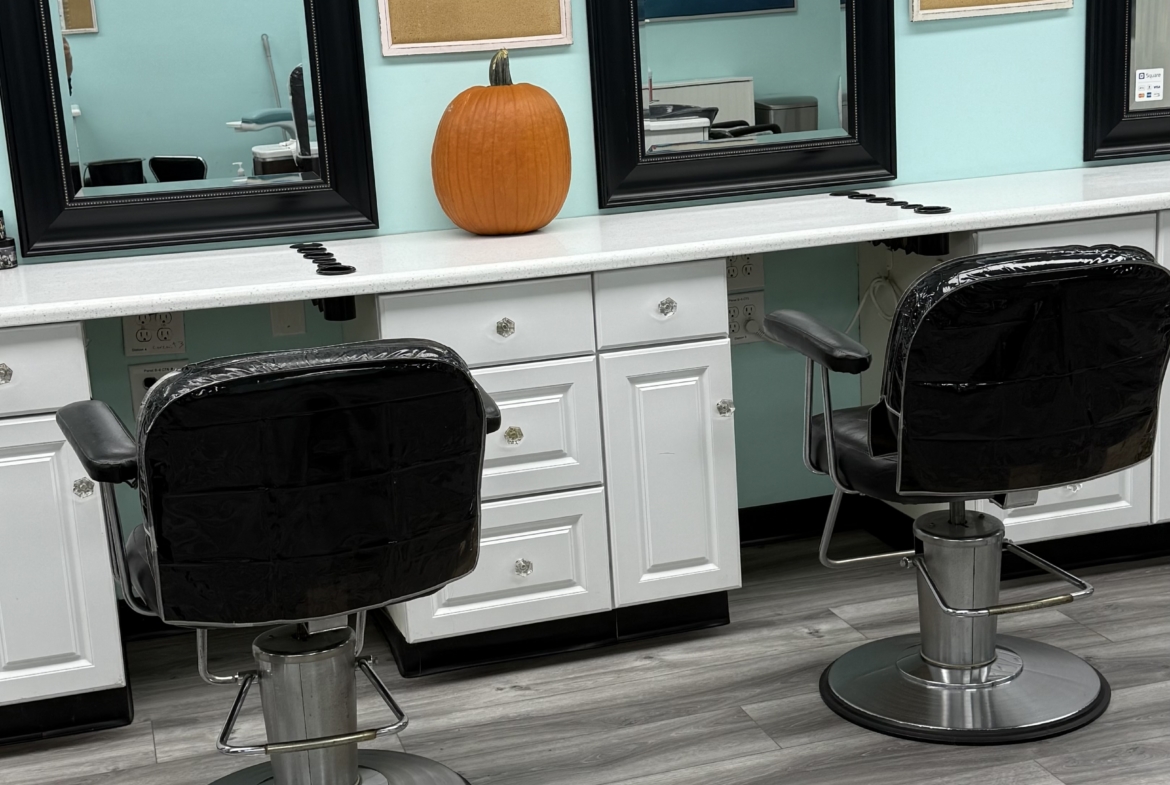 Modern salon station with black-framed mirrors, white cabinetry, and styling chairs.