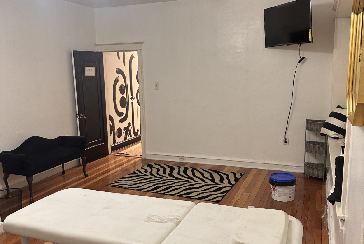 Modern salon rental space with massage table, TV, and stylish interior design.