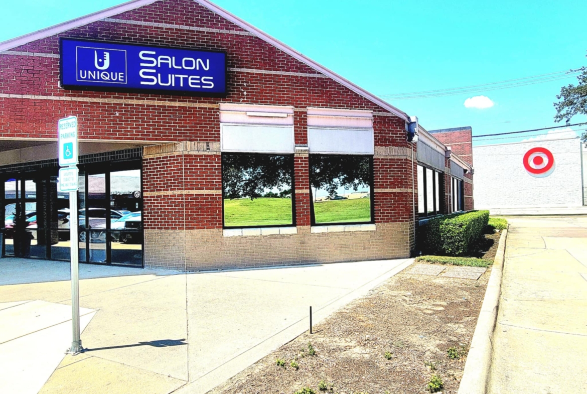 Modern brick salon suite building with large windows and parking lot.