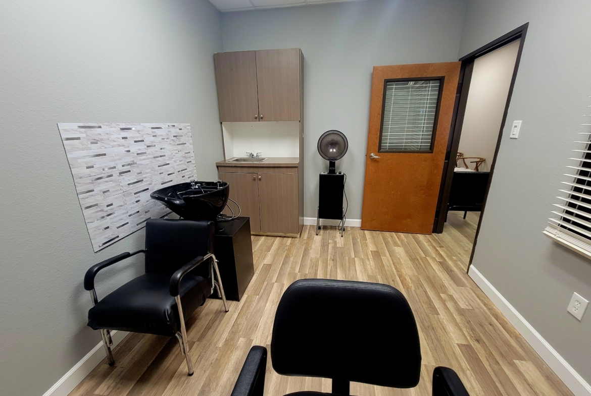Hair salon room with shampoo station, chairs, and functional setup for rent or lease.