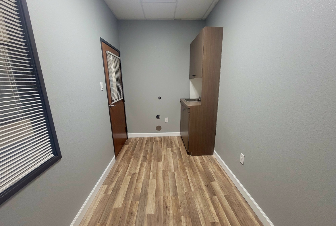 Bright, clean salon workspace for rent with window blinds and kitchenette.