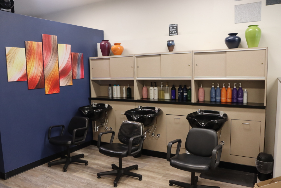 Bright salon hair washing area with shampoo stations, stylish decor, and colorful artwork.